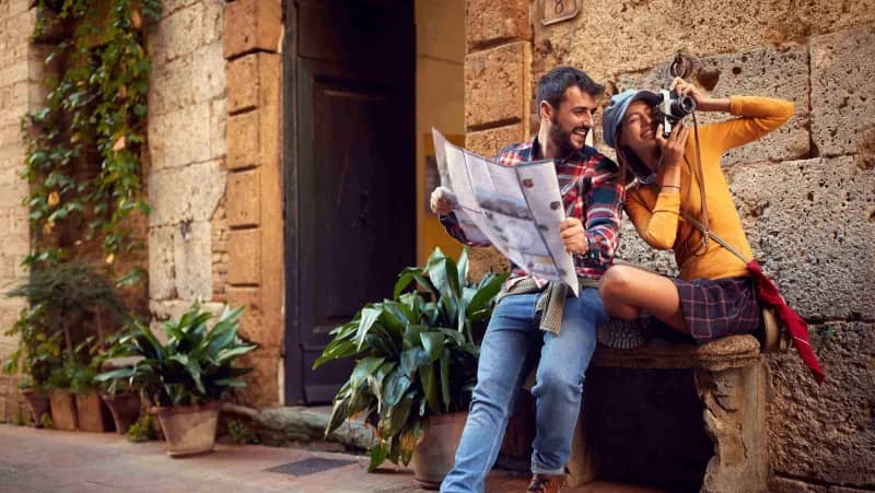 Smiling couple with camera and brochure, planning their travel adventures for the day