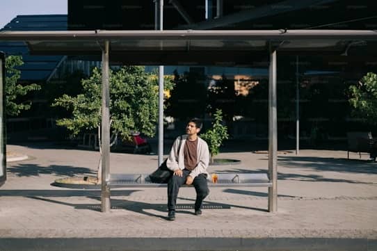 A man sitting on a bench at a bus stop